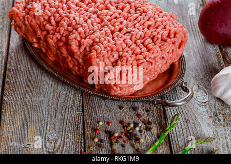 Frisches rohes Hackfleisch Hackfleisch auf alten Holz Hintergrund und Gemüse Stockfoto