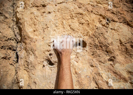 Erntegut männliche Hand in weißer Kreide Pulver hängend auf rauen Felsen während dem Aufstieg Stockfoto