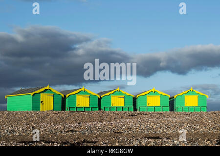 Gelbe und grüne Strandhütten in einer Reihe an einem sonnigen Tag Stockfoto