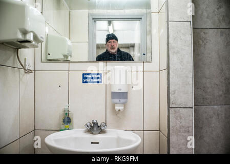 Bärtiger Mann im Spiegel, jetzt unterzeichnen sie ihre Hände waschen, öffentliche Toilette, Händetrockner, Flüssigseife, Stockfoto