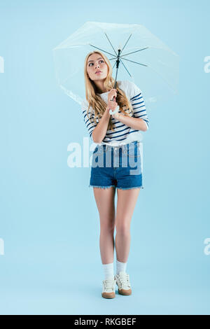 Frau in casual Outfit holding Umbrella auf blauem Hintergrund Stockfoto