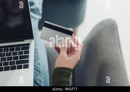 7/8-Ansicht von Frau mit Kreditkarte in der Nähe von Laptop Stockfoto
