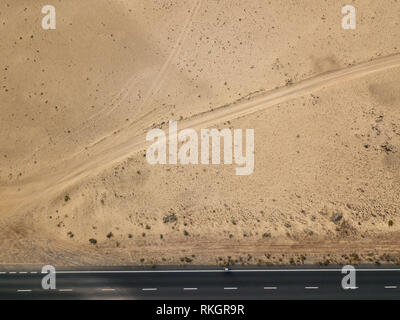 Luftaufnahme von einer Straße in die Wüste, Radfahrer Racing auf dem Fahrrad auf dem schwarzen Asphalt. Outdoor Sport, Radfahren, Tourismus. Lanzarote, Spanien Stockfoto