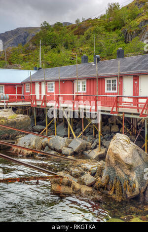 Fisherman's Häuser auf Stelzen gebaut in den Hafen von Nusfjord, ein traditionelles Fischerdorf entlang der Vestfjorden Stockfoto