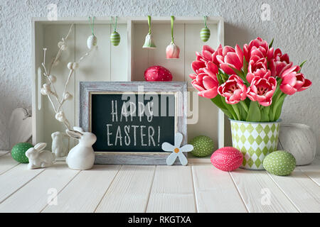 Frühling Hintergrund mit Ostern Dekorationen, Tulpen und ein Chalk board. Text "Frohe Ostern" auf der Platine Stockfoto