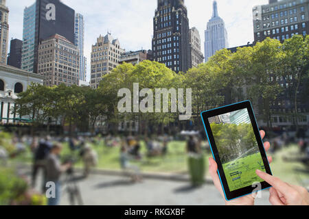 Weibliche finger berühren Tablet mit leeren Bryant Park Bild im Bild. Absichtlich verschwommene Bild eines Bryant Park (NYC) ist im Hintergrund. Ein Stockfoto