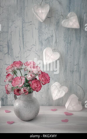 Valentines Tag noch Leben mit leerem Papier Karte, rosa Rosen und girlande Lichter in Form von Papier Herzen auf rustikalen Hintergrund Stockfoto