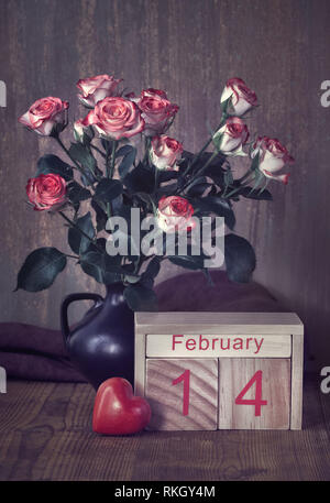 Valentinstag noch Leben mit Holz- Kalender, Rosen und Herzen auf rustikalem Holz Stockfoto
