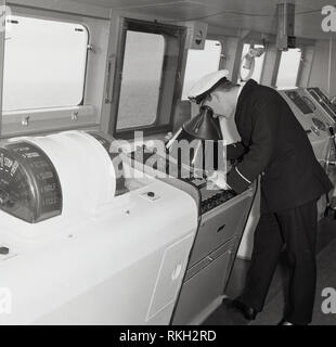 1960 s, union-castle Kreuzfahrtschiff, einem uniformierten Offizier auf der Brücke des Schiffes in der Leitwarte oder Deck auf einem Radar Instrument suchen. Stockfoto