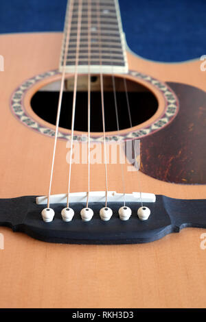 Klassische akustische sechs Saiten natürliche Farbe Top von mit Cutaway Fragment mit langen Hals auf Jeans Hintergrund vertikale Ansicht Nahaufnahme fichte Gitarre Stockfoto