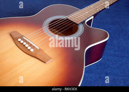Klassische akustische sechs Saiten sunburst Farbe Top von mit Cutaway Fragment auf Jeans Hintergrund Seitenansicht closeup Fichte Gitarre Stockfoto