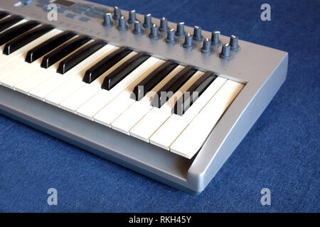 Elektronische Synthesizer Keyboard mit vielen Drehknöpfe denim Hintergrund Seitenansicht closeup Stockfoto