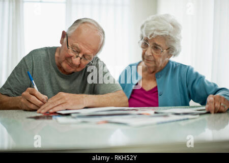 In dem Bestreben, ältere Paare anmelden Papierkram, während Sie durch Ihre große Stapel von Rechnungen. Stockfoto