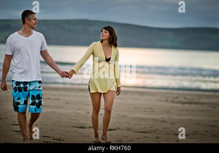 Paar mittleren Alters gehen Hand in Hand am Strand. Stockfoto