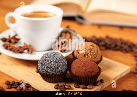 Kaffee eine Tasse heißen Kaffee und Kuchen auf einem Holztisch mit einem offenen Buch. Eine weiße Tasse schwarzen Kaffee durch eine kleine Menge von gerösteten Co umgeben Stockfoto