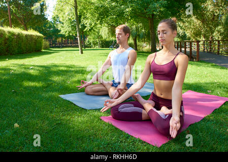 Volle Länge schoss der jungen Frau und Mann Üben Yoga zusammen Outdoor. Stockfoto
