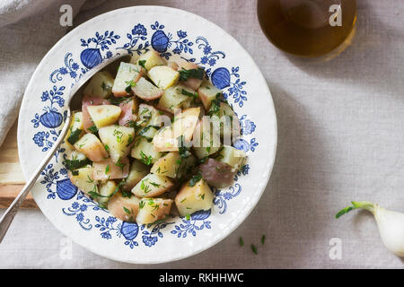 Traditionelle kalte Kartoffelsalat mit Zwiebeln und Kräutern auf einem Leinen Tischdecke Hintergrund. Im rustikalen Stil. Stockfoto