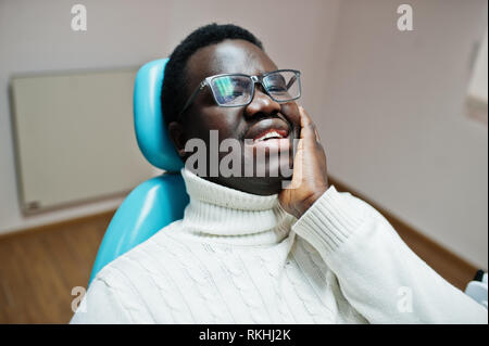 Afrikanische amerikanische Mann mit Zahnschmerzen in einem behandlungsstuhl sitzen und müssen helfen, männlichen Patienten Schmerzen. Zahnheilkunde medizinische. Stockfoto