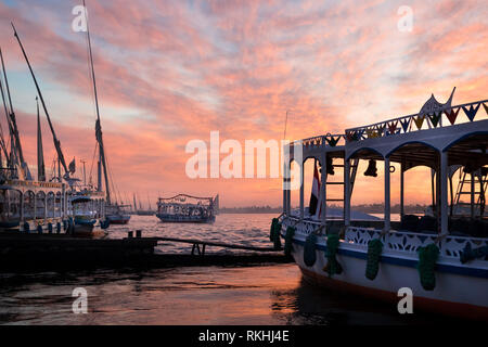 Verschiedene Boote auf dem Nil in Luxor, Ägypten, mit einer schönen rosa Sonnenuntergang Himmel im Hintergrund Stockfoto