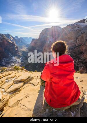 Junge Frau mit Blick auf die Entfernung zum Angels Landing zu Zion Canyon, Angels Landing Trail, im Winter, Berglandschaft Stockfoto