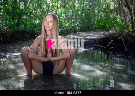 Junge Frau mit Yoga (Garland Pose-malasana) in einer natürlichen Umgebung - Fort Lauderdale, Florida, USA Stockfoto