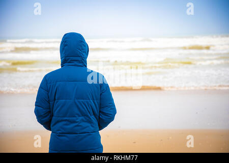 Junge Mann in der Jacke auf sandigen Strand von Rimini im Winter, Italien Stockfoto