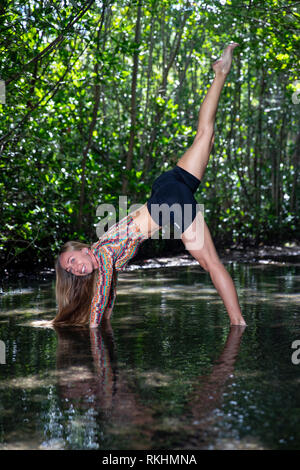 Junge Frau mit Yoga (nach unten schauenden Hund Split (dreibeiniger Hund) in einer natürlichen Umgebung - Fort Lauderdale, Florida, USA Stockfoto