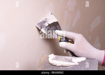 Hand mit Spachtel Reparatur Wand, von Hand mit einem Spachtel Spachtel mit feinspachtel Struktur einfügen, Anwendung der Schicht von putty Kelle, arbeiten mit Stockfoto