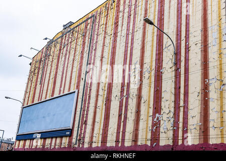 Die bröckelnden Abblättern alter Lackierung und Alterung auf einer alten Mauer Mietshaus mit Straßenlaterne. Die Malerei beginnt zu verblassen und lose Farbe. Stockfoto