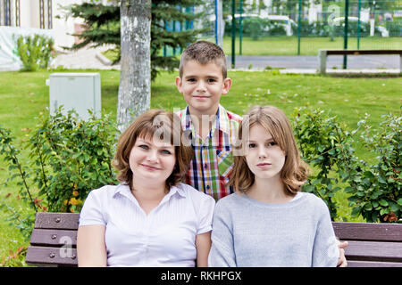 Glücklichste Mutter mit Tochter und Sohn sind auf einer Bank sitzen Stockfoto