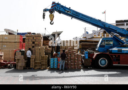 Einen Kran verwendet wird schwere Ladung auf ein Ozean, hölzernen Dhow (arabisches Boot) mit Cargo auf dem Dubai Creek in Dubai geladen in t wird geladen Stockfoto