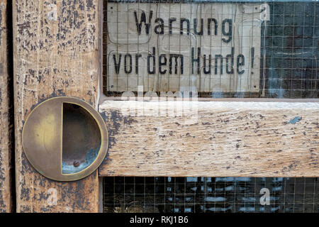 Altes Schild an der Tür mit dem Text "Warnung vor dem Hund". Stockfoto