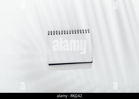 Leere notepad auf weißem Hintergrund mit palm leaf Schatten, Blick von oben. Stockfoto