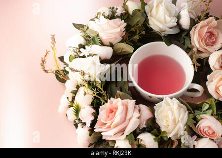 Teetasse in einem rosa und weiße Rose Wreath auf einem rosa Hintergrund Stockfoto