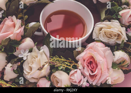 Teetasse in einem rosa und weiße Rose Wreath auf einem rosa Hintergrund Stockfoto