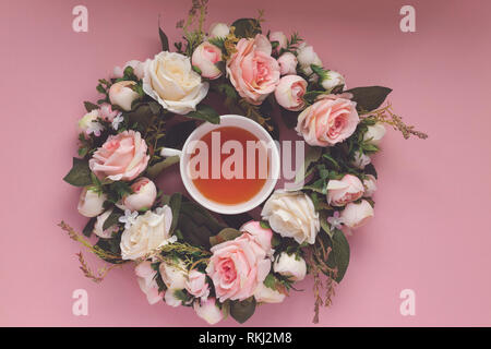 Teetasse in einem rosa und weiße Rose Wreath auf einem rosa Hintergrund Stockfoto