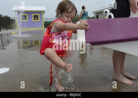 Ein Kleinkind wäscht ihre Füße in Wasser bei einer splash Pad während des Sommers. Stockfoto