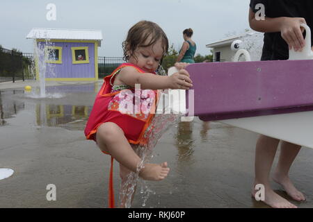 Ein Kleinkind wäscht ihre Füße in Wasser bei einer splash Pad während des Sommers. Stockfoto