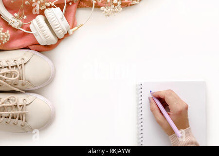 Weibliche Hand schreiben in Notizbuch aus Papier auf weißer Tisch. Mode Frauen coral Zubehör eingestellt. Stockfoto