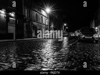 Regen durchnässt gepflasterten Straße bei Nacht, Kelso, Schottland Stockfoto