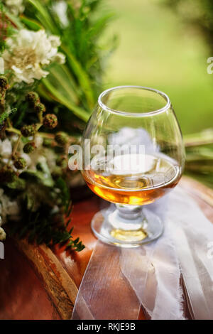 Gläser mit Brandy gefüllt, ein Glas auf dem Tisch neben der Blume Stockfoto