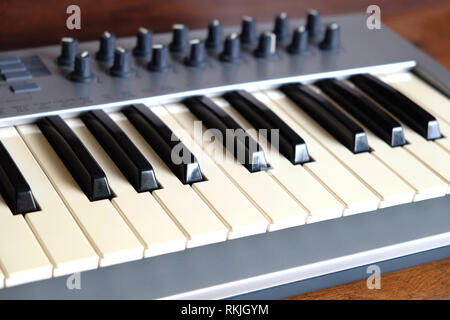 Elektronische Synthesizer Keyboard mit vielen Reglern in Silber Kunststoff auf Holz Hintergrund Seitenansicht closeup Stockfoto