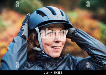 Eine Nahaufnahme der aktiven älteren Frau, die im Freien, auf dem Fahrrad Helm. Stockfoto