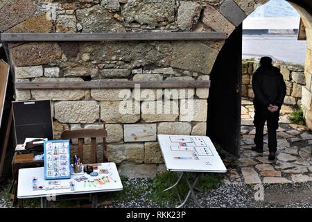 Izmir, Türkei. 28 Jan, 2019. Eine ältere Künstlerin mit Souvenirs und seine Gemälde geht durch ein Tor von Genoese-Ottoman fünf Tore Schloss in der Altstadt. Credit: Altan Gochre | Verwendung weltweit/dpa/Alamy leben Nachrichten Stockfoto