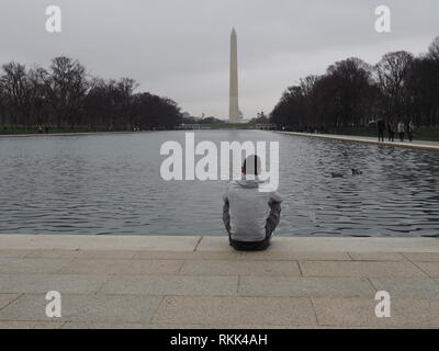 Mann Sitze durch die reflektierenden Pool am Lincoln Memorial in Washington DC, USA Stockfoto