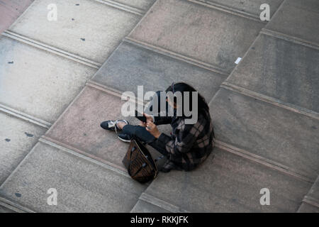 Junge Frau sitzt auf dem Dach der Kathedrale Duomo di Milano und Suchen in Smartphone Stockfoto