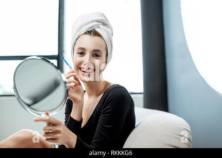 Porträt eines lächelnden Frau, die Ihre Zähne mit Gel und Kunststoff Hosenträger, sitzen auf der Couch zu Hause Stockfoto