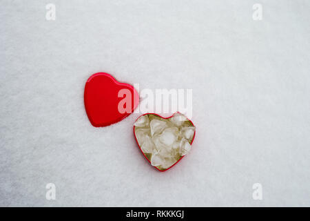 Blick von oben auf die rote herzförmige Box mit Eis Jungen innerhalb und der Deckel an der Seite, im Schnee. Kopieren Sie Platz für Ihren Text. Stockfoto