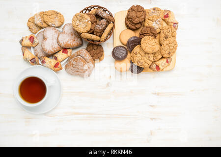 Flach der Chocolate Chip Cookies und einer Tasse Tee auf einem weißen Holztisch. Stockfoto