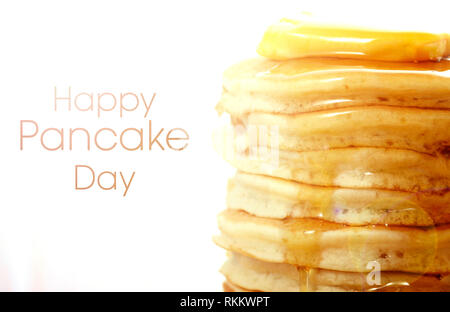 Stapel Pfannkuchen closeup, mit Nieselregen Honig Sirup, mit Happy Pancake Day text und Objektivreflexionen. Stockfoto